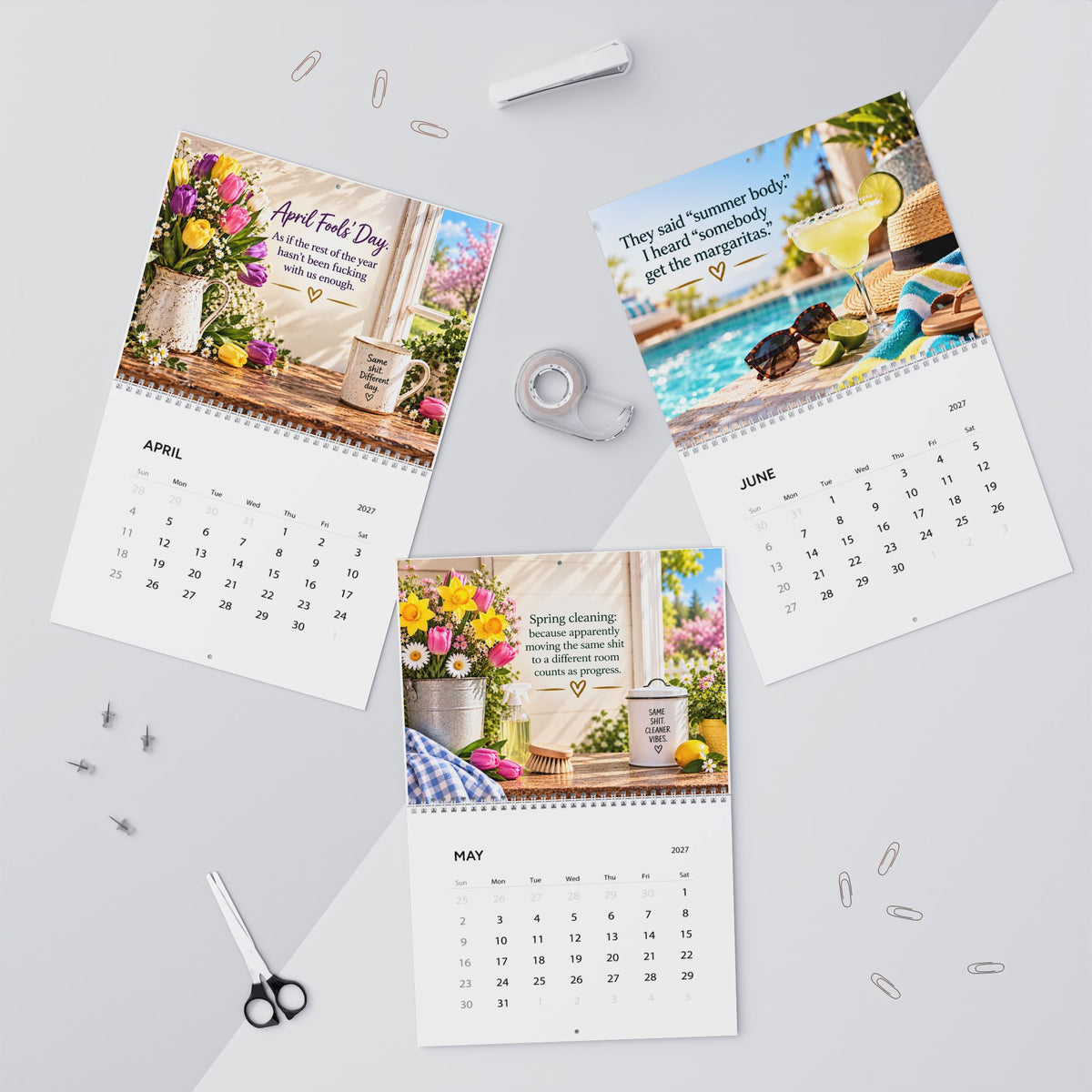 Three spiral-bound desk calendar pages laid out on a light gray surface with stationery props. The pages show monthly calendars with colorful floral and beach-themed printed designs and motivational text for April, June, and May.