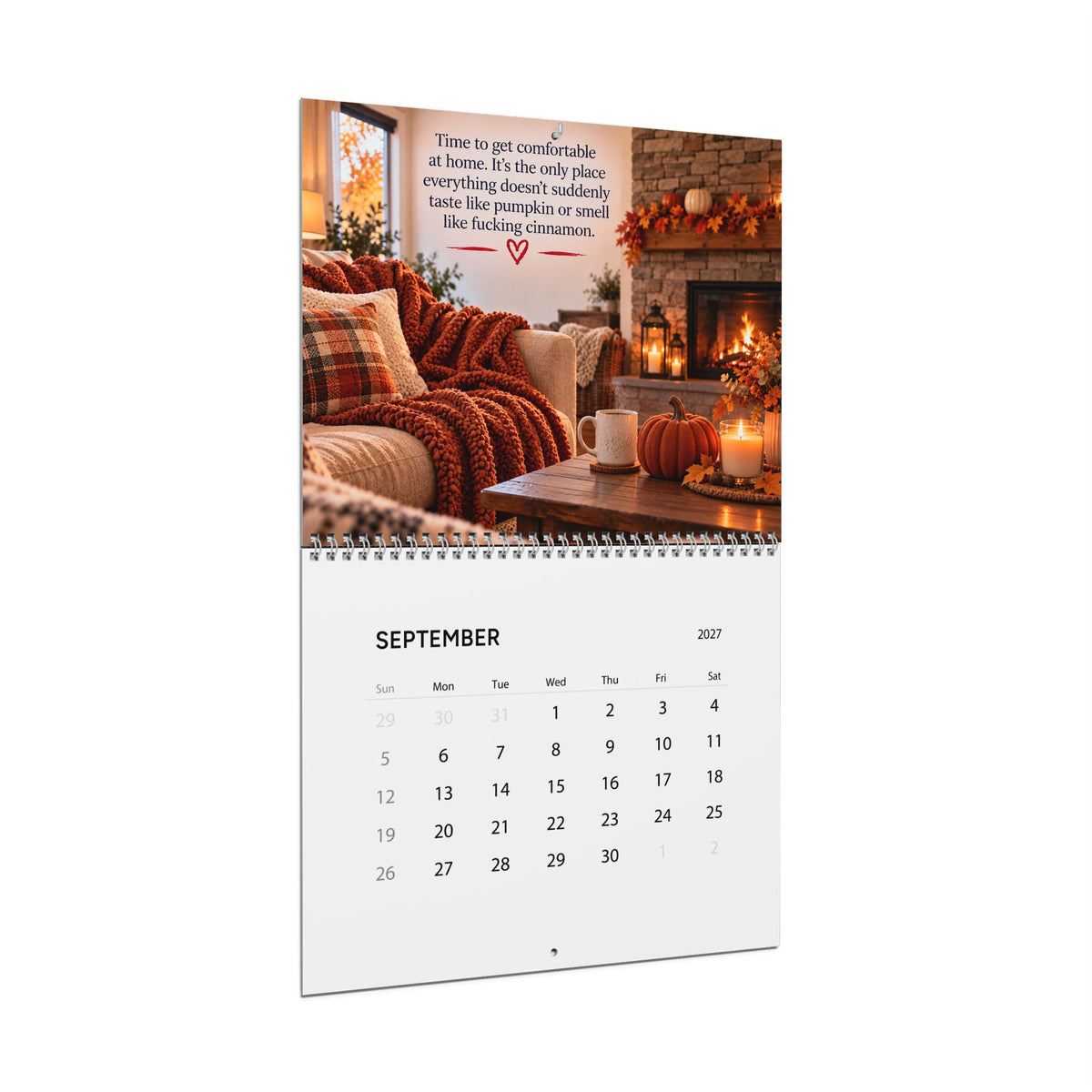 A spiral-bound desk calendar page shown upright on a white background. The top portion features a cozy autumn living room scene with a fireplace, plaid pillows, candles, and a quote.